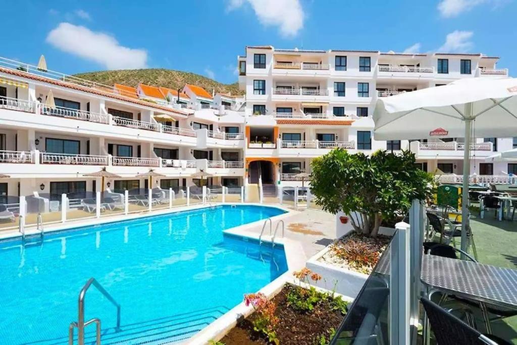 een hotel met een zwembad voor een gebouw bij Apartamento Shakespeare in Los Cristianos LD118 in Los Cristianos