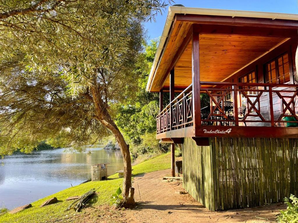 a wooden building with a balcony next to a river at Areena Riverside Resort in Kwelera