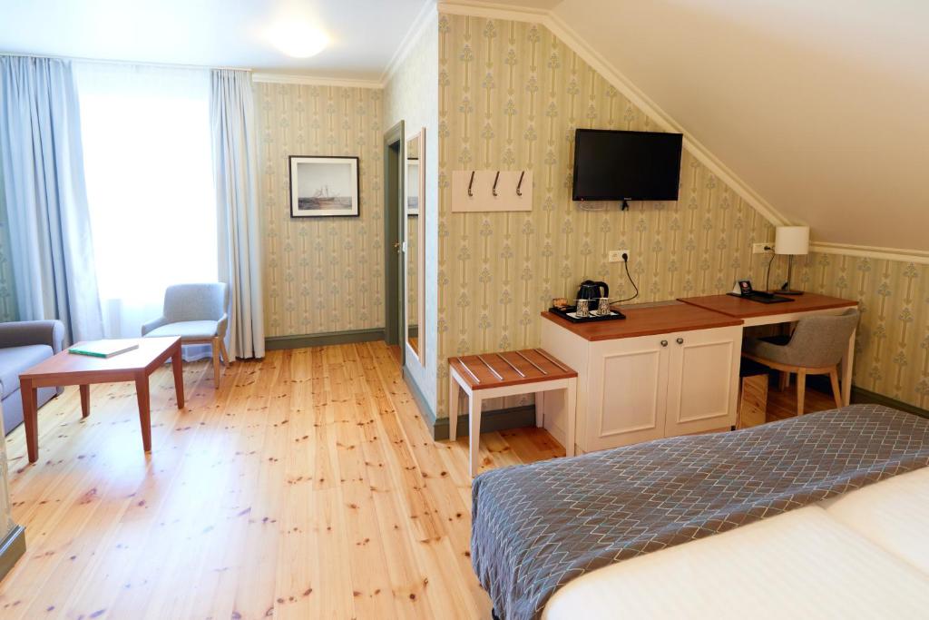 a bedroom with a bed and a desk with a tv on the wall at Fosshotel Eastfjords in Fáskrúðsfjörður
