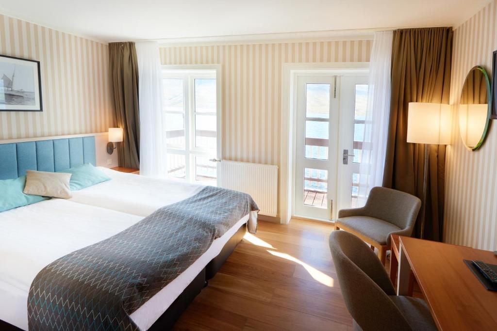a bedroom with a bed and a desk and a chair at Fosshotel Eastfjords in Fáskrúðsfjörður