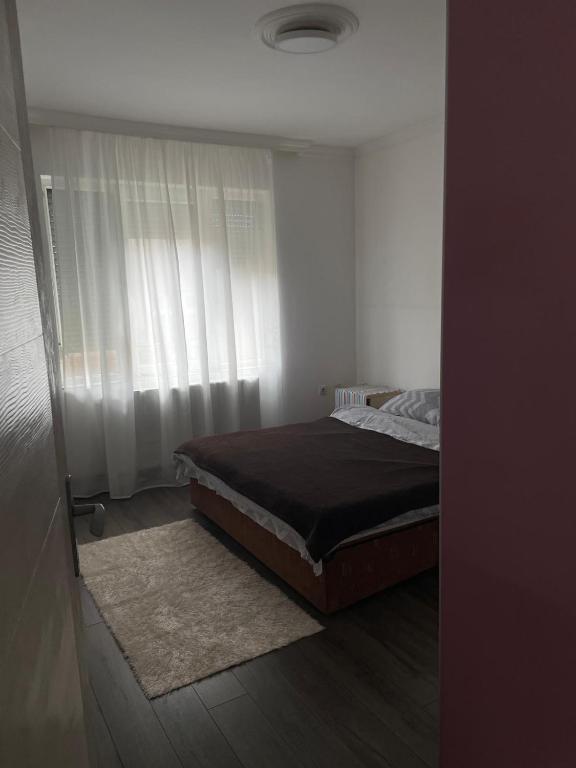 - une chambre avec un lit et une fenêtre avec des rideaux dans l'établissement Aurora, à Kuršumlija