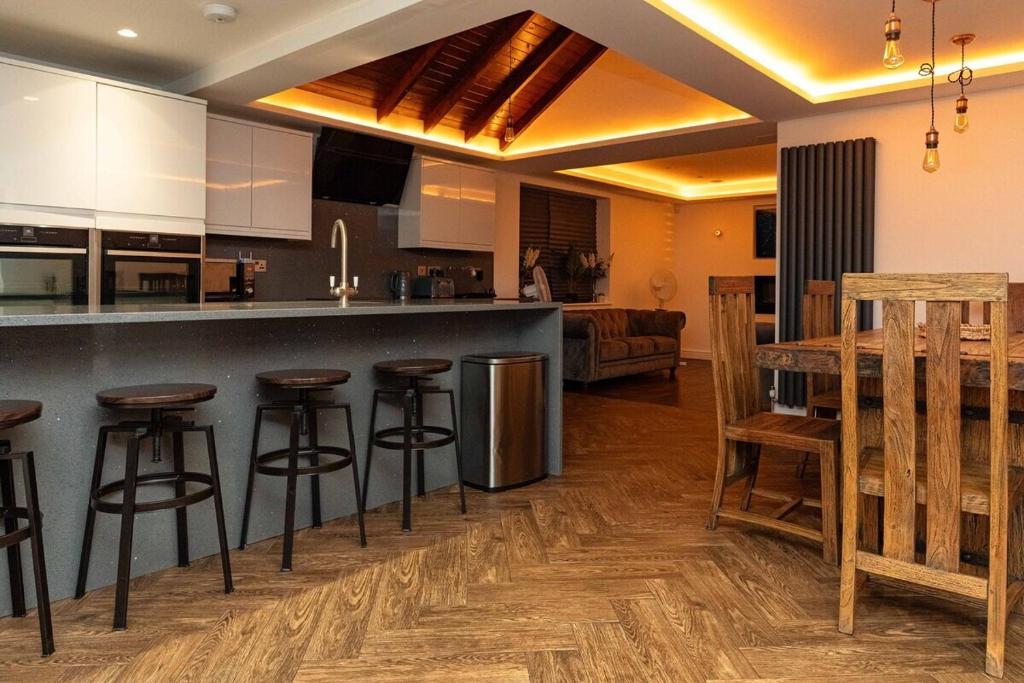uma cozinha e sala de estar com um balcão e bancos em Bonneville House, Private Jacuzzi and Modern Interior em Londres