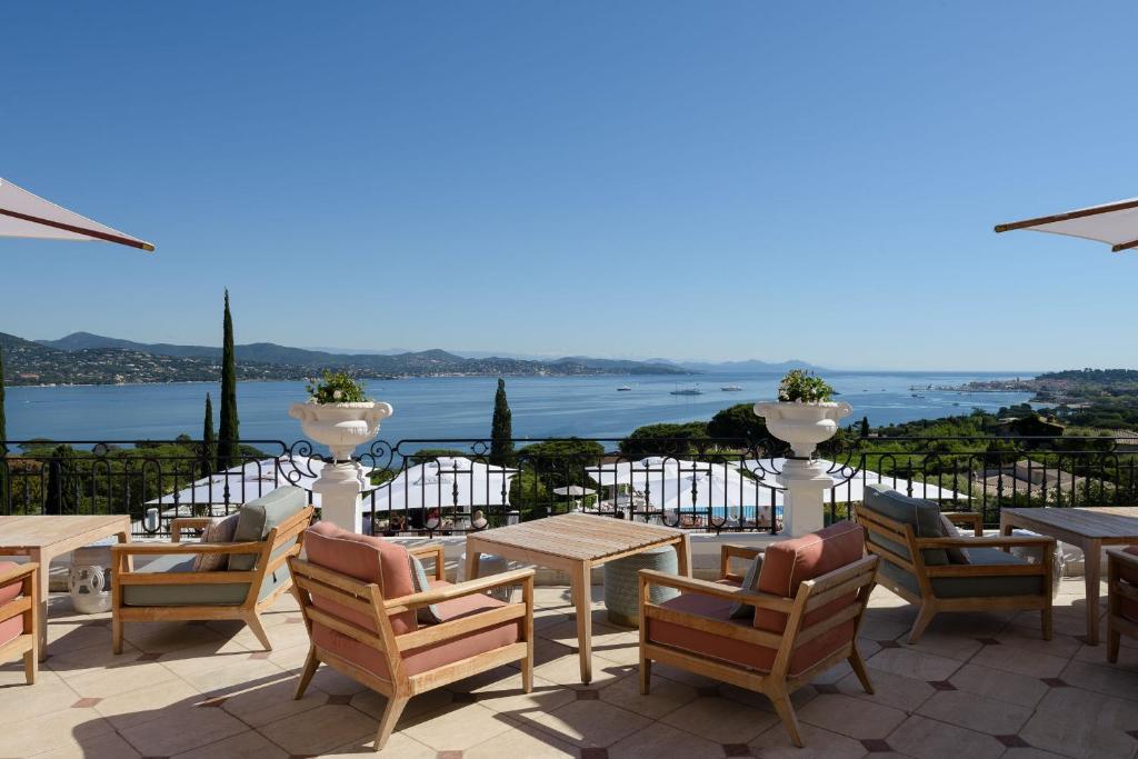 a patio with tables and chairs and a view of the water at Althoff Hotel Villa Belrose in Saint-Tropez