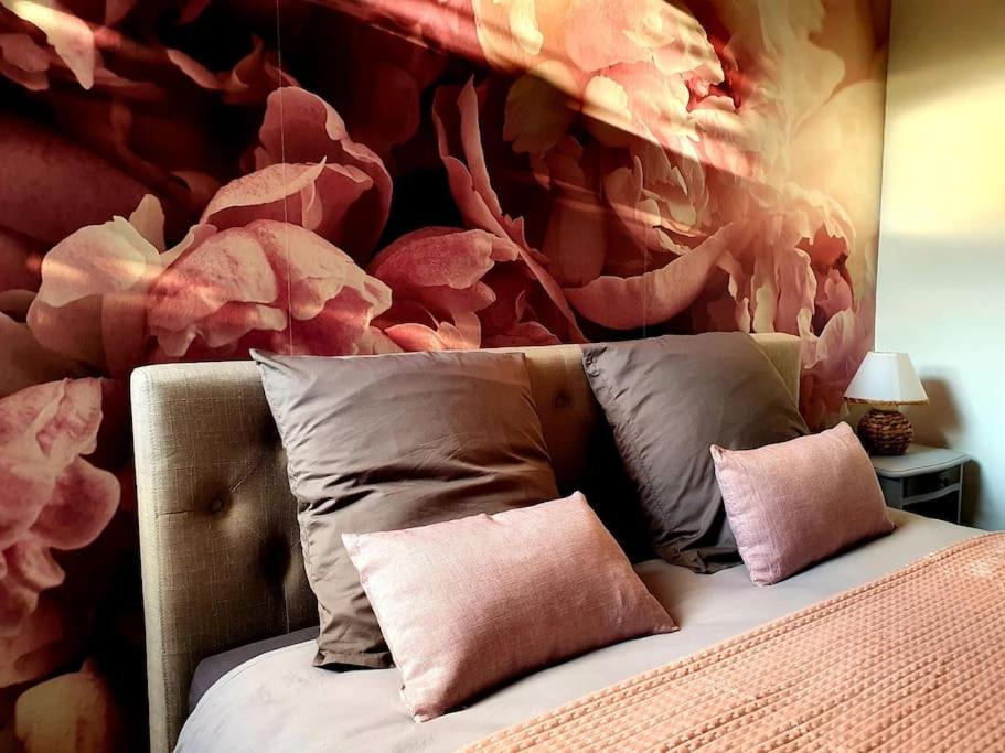 une chambre avec un lit avec un mur de fleurs rouges dans l'établissement Les Pivoines, à Mont-sous-Vaudrey