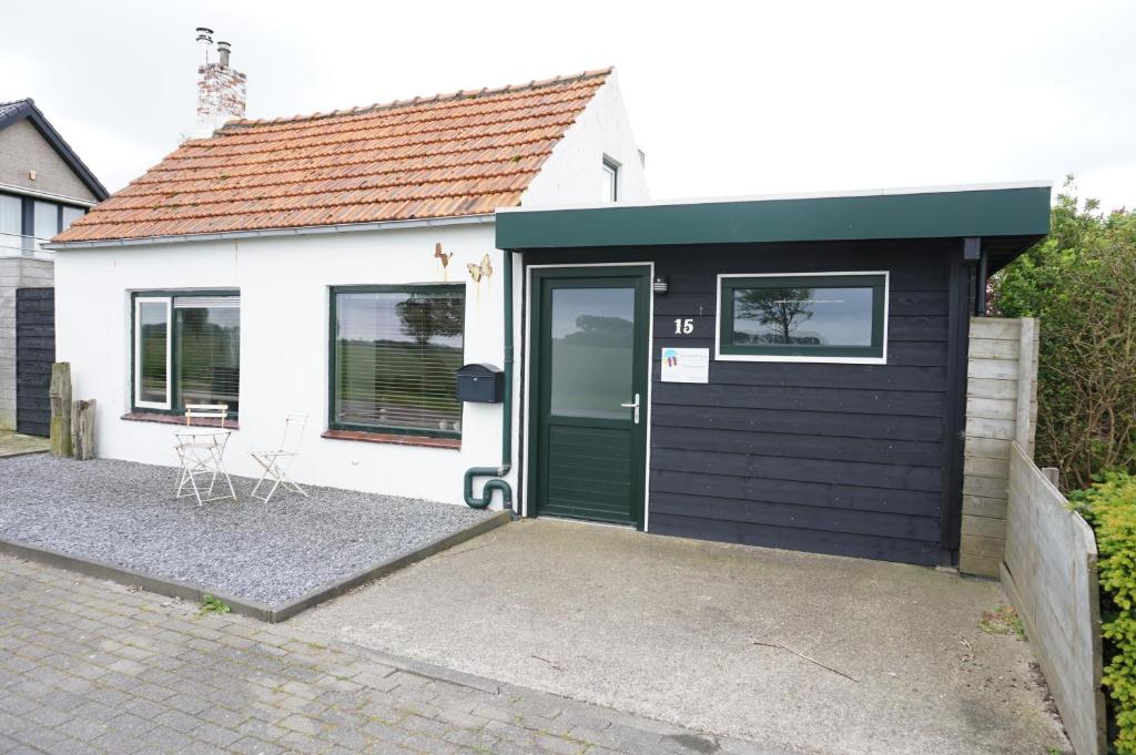 una pequeña casa blanca con una puerta verde en Kustverhuur, 't Uusje Nieuwvliet, en Nieuwvliet