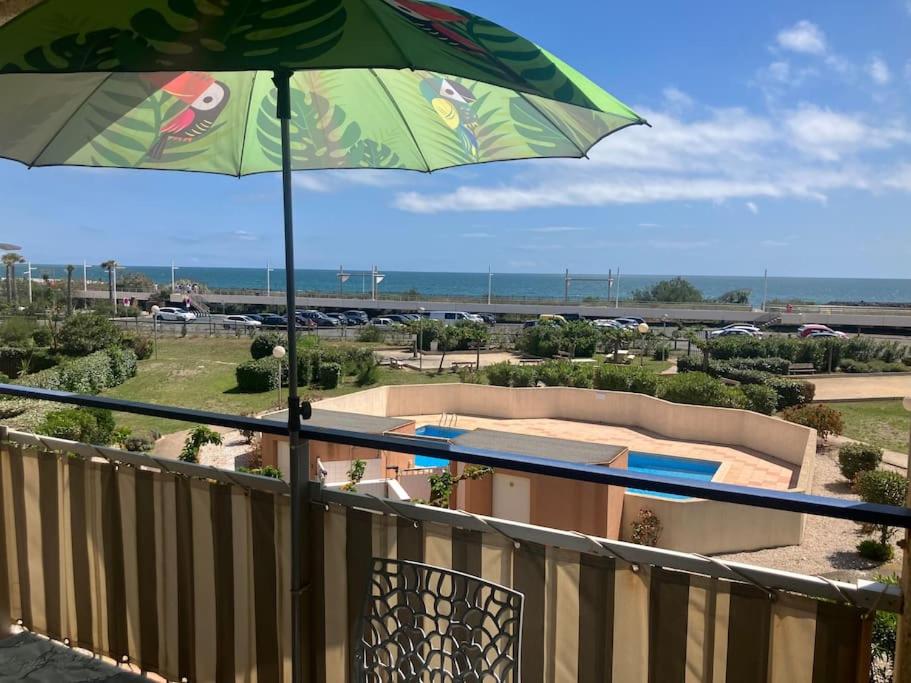 - un parasol vert installé au-dessus d'un balcon dans l'établissement VIAS PLAGE - Apt climatisé pour 4 personnes piscine collective, à Vias