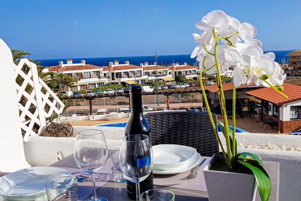 una mesa con una botella de vino y un jarrón con flores en Precioso apartamento con piscina y vista al mar en San Miguel de Abona