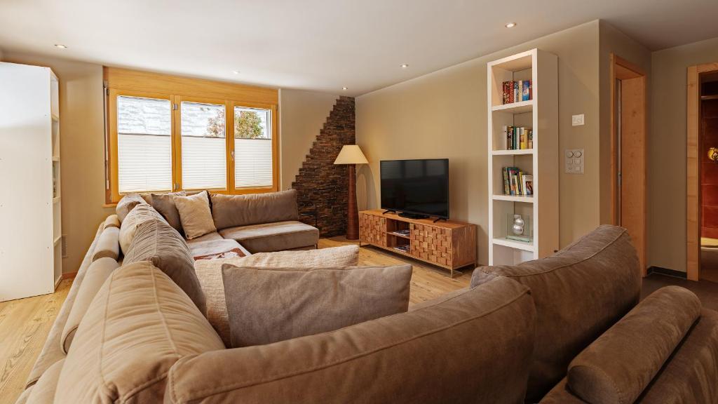 a living room with a large couch and a television at Casa Della Luce Apartments in Zermatt