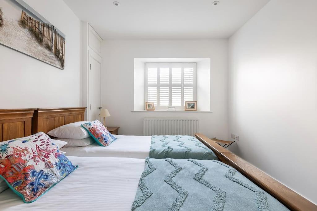 a bedroom with two beds and a window at Porthminster View Luxury Sea Views Balcony, Parking, Pool, Spa & Gym in St Ives