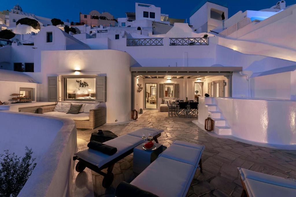 a villa with white walls and tables and chairs at 180° Caldera by Stylish Stays in Firostefani
