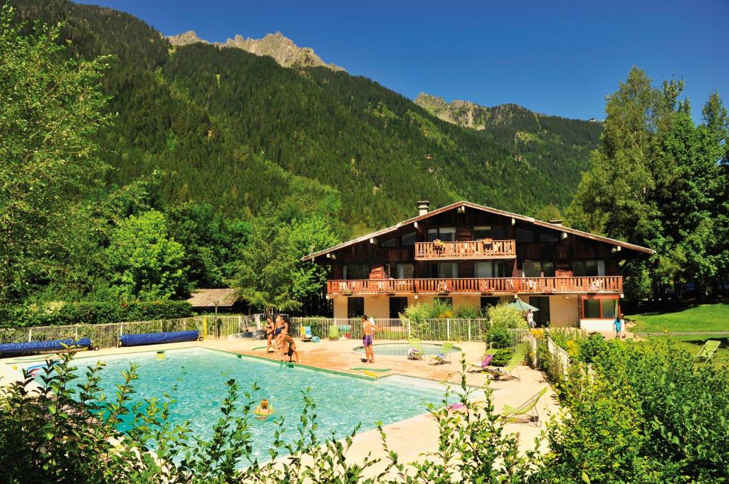 a building with a swimming pool in front of a mountain at VTF Les Econtres in Chamonix