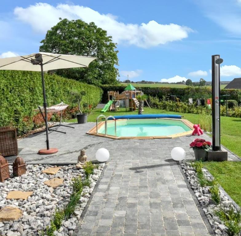 een achtertuin met een zwembad en een parasol bij One bedroom house with shared pool enclosed garden and wifi at Hamois in Hamois