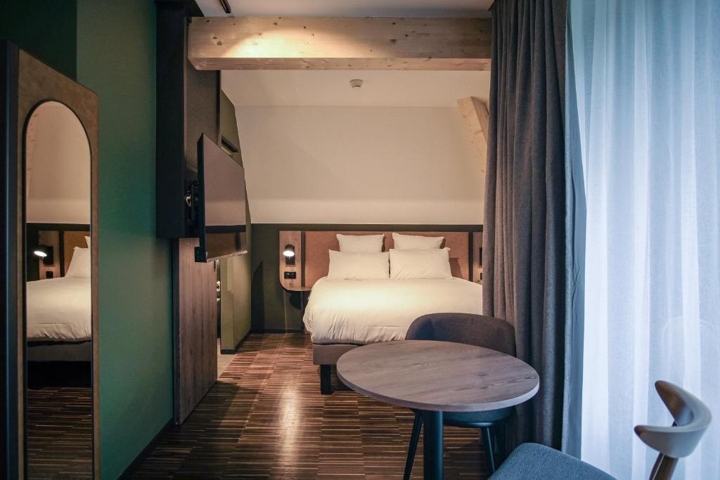 a hotel room with a bed and a table at Hota Hotel Saint-Imier in Saint-Imier