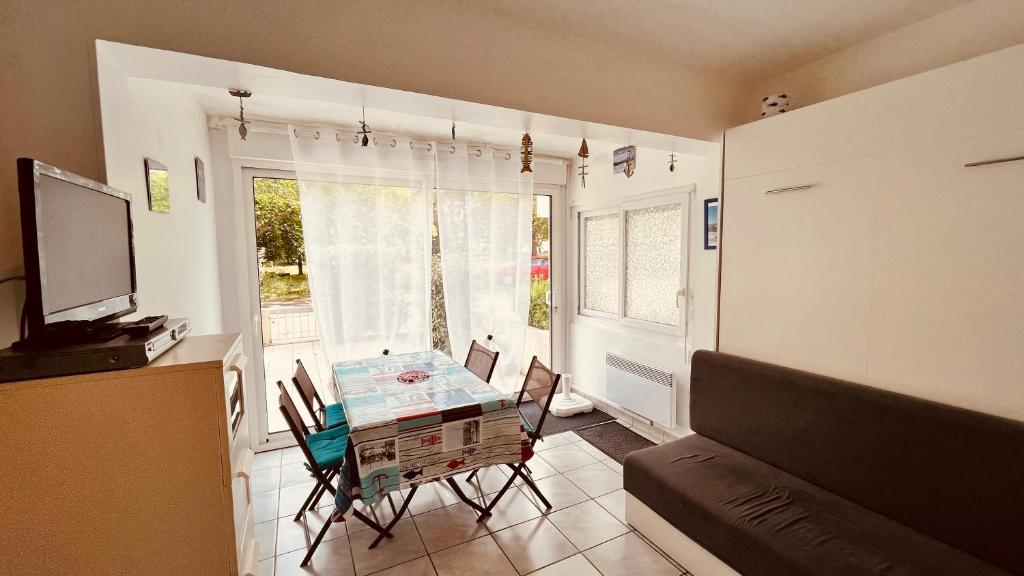 un salon avec une table avec des chaises et une télévision dans l'établissement Appart du parc, emplacement rêvé, à Saint-Jean-de-Monts