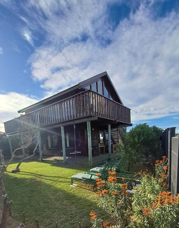 a house with a deck and a yard with flowers at Lili Ellipsis in Pearly Beach