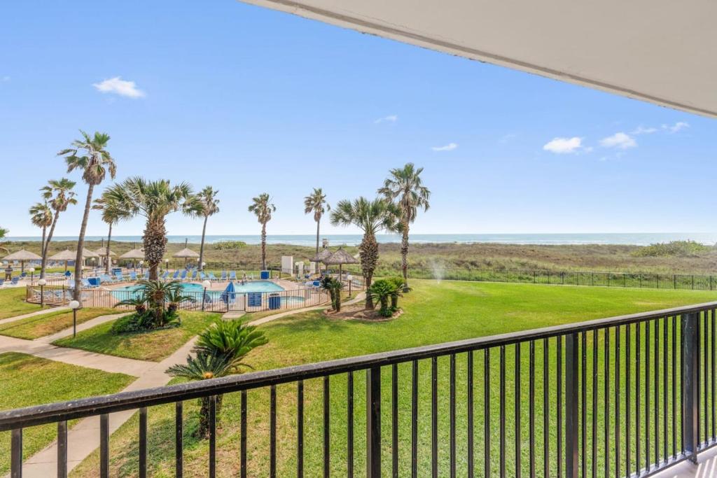 a balcony with a view of a pool and palm trees at Saida II Beachfront Oasis in South Padre Island