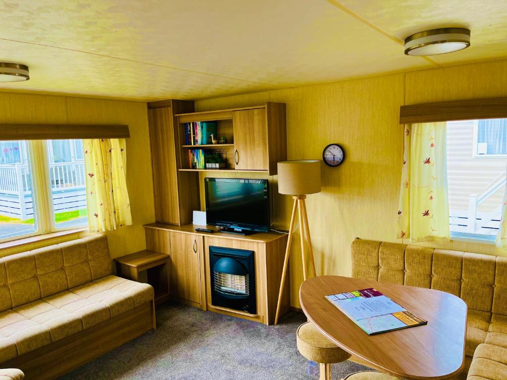a living room with a couch and a tv and a table at Meadow View Horizon Static Caravan in Barnstaple