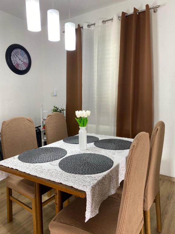 une table à manger avec quatre chaises et un vase de fleurs dans l'établissement Apartments and Rooms Pavla, à Senj