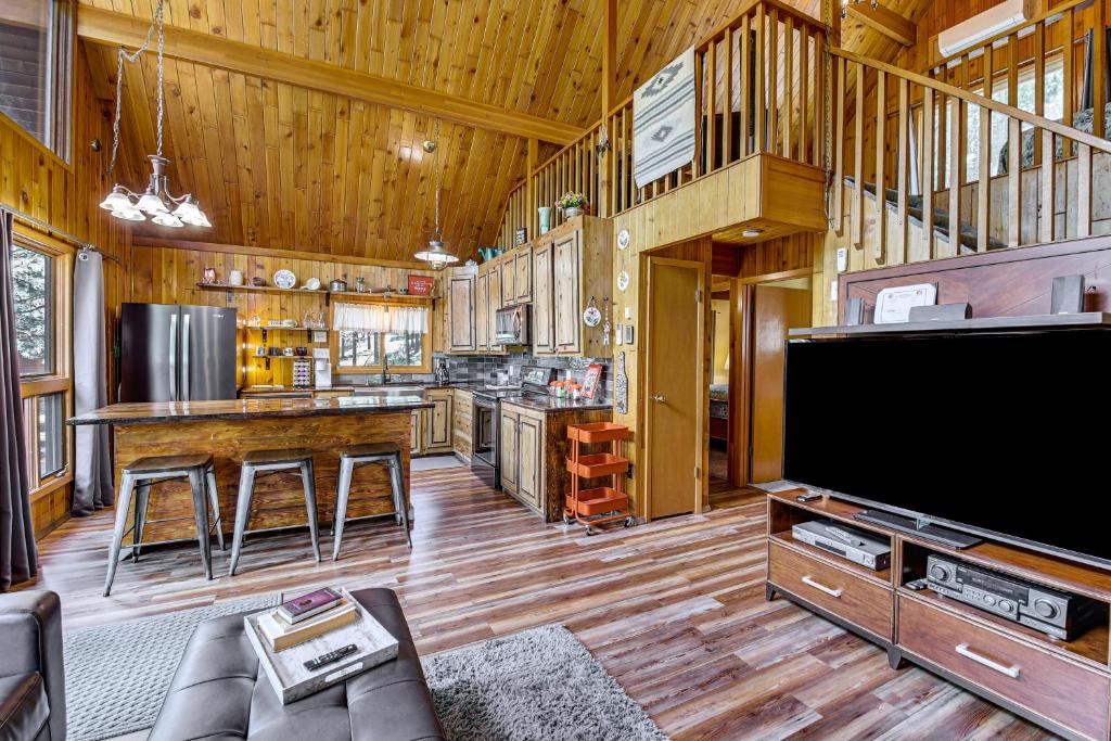een woonkamer met een grote televisie en een keuken bij Modern Black Hills Cabin with Loft and Wraparound Deck in Rapid City