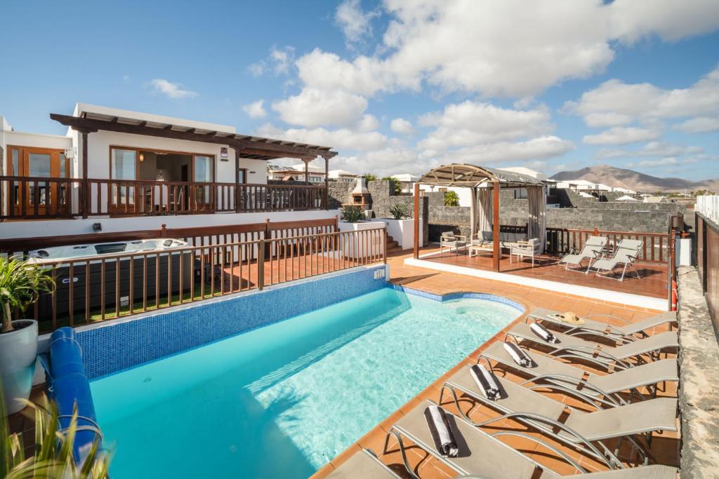 einen Pool mit Liegestühlen neben einem Haus in der Unterkunft Villa 61 PlayaBlanca Lanzarote Pool Spa in Playa Blanca