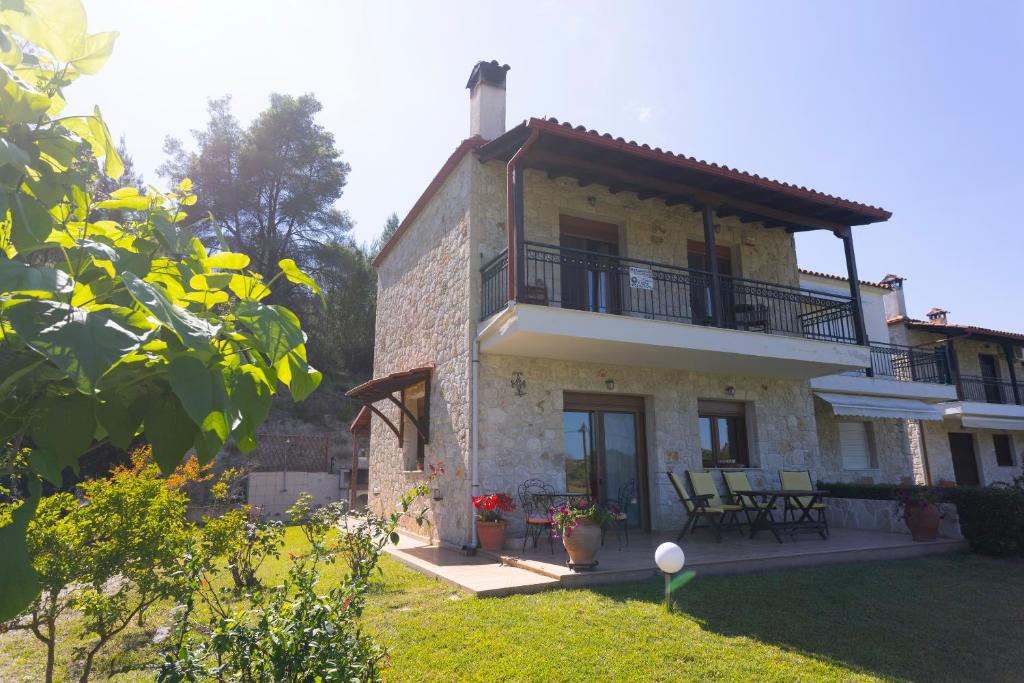 a large stone house with a balcony and patio at The Emerald Garden Maisonette in Siviri