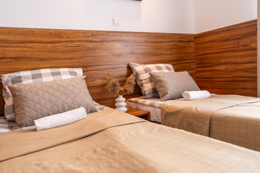 two beds in a room with wooden walls at MAX Apartamenty - Pokoje - Domki - Restauracja - Basen in Mielno
