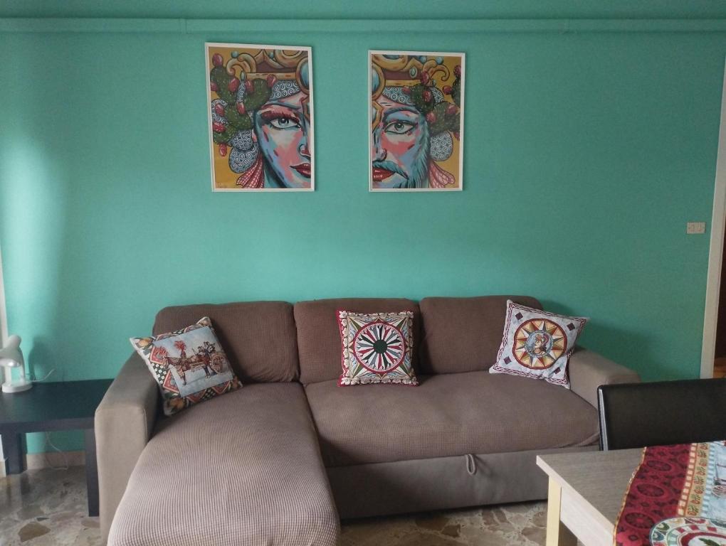 eine Couch in einem Wohnzimmer mit drei Bildern an der Wand in der Unterkunft Casa Giorgia in Cefalú