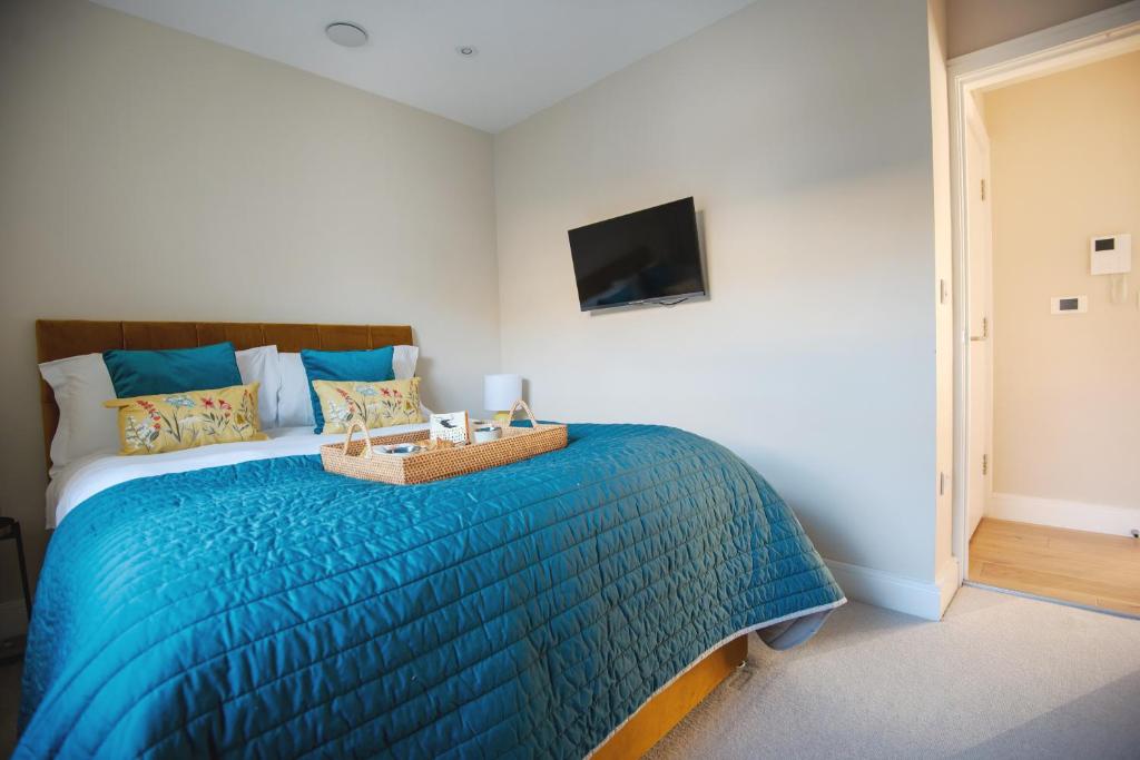 1 dormitorio con 1 cama con edredón azul y TV en Dream Stays Bath - John Street en Bath