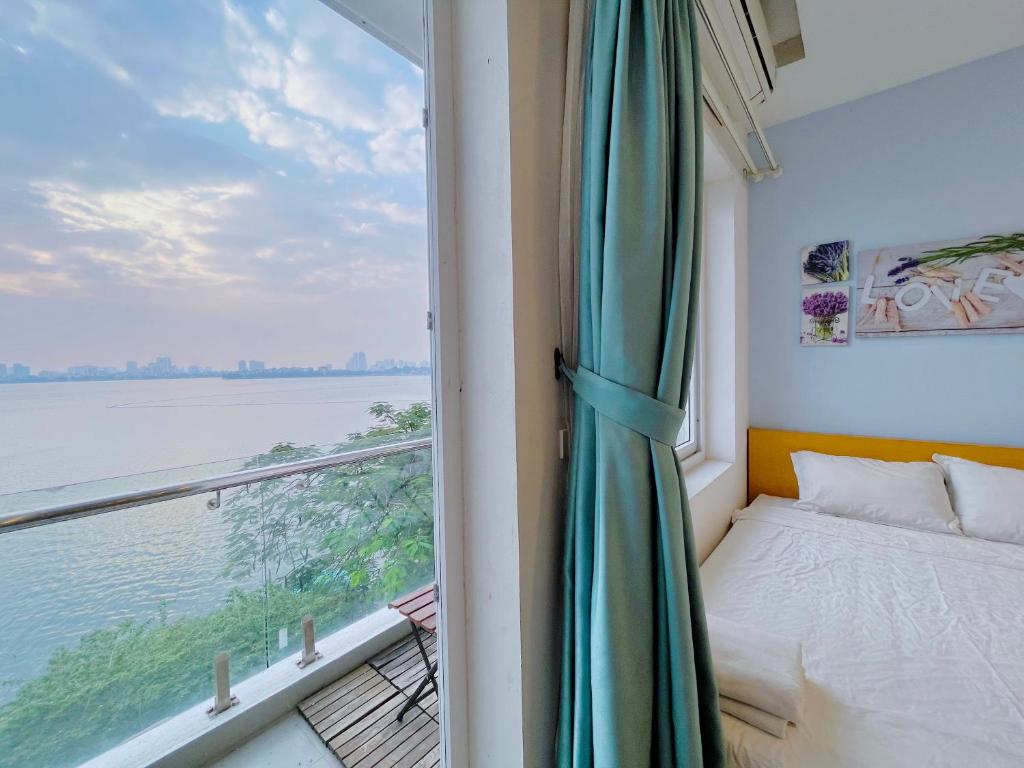 um quarto com uma janela com uma cama e uma vista em Hanoi Home 2 - Lake View Apartment em Hanói