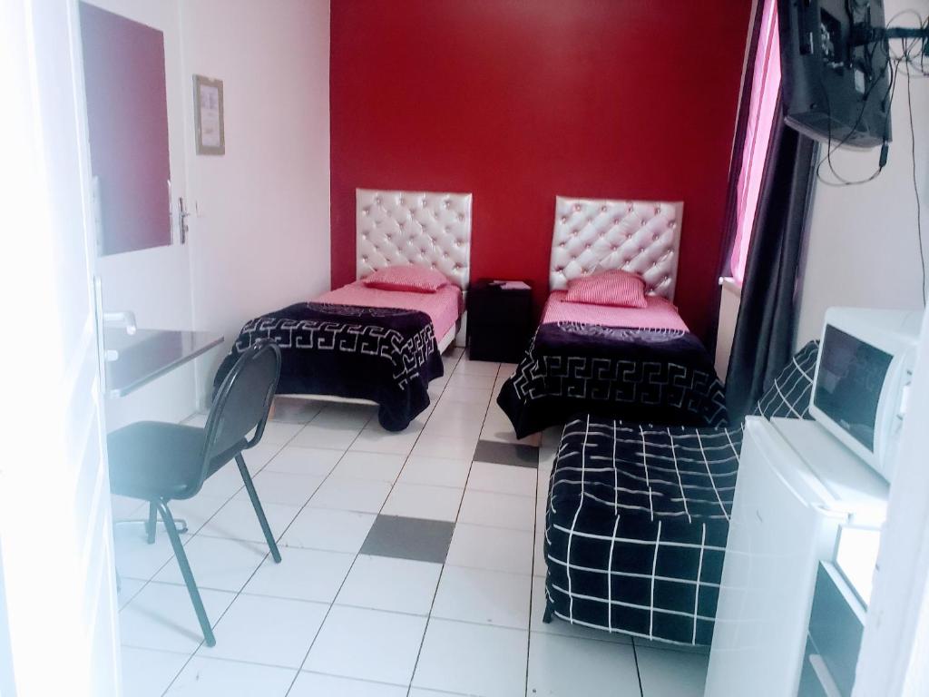um quarto com duas camas e uma parede vermelha em LE CEDRE em Saint-Denis