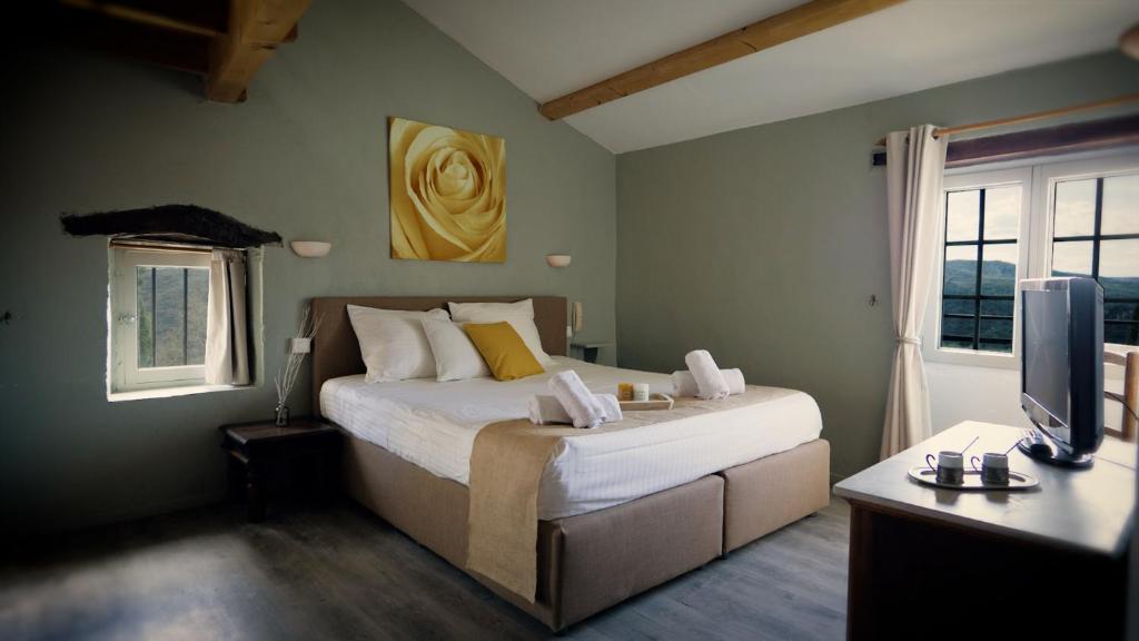 a bedroom with a bed and a desk and a television at Hôtel restaurant Clos des Sullys in Montclus