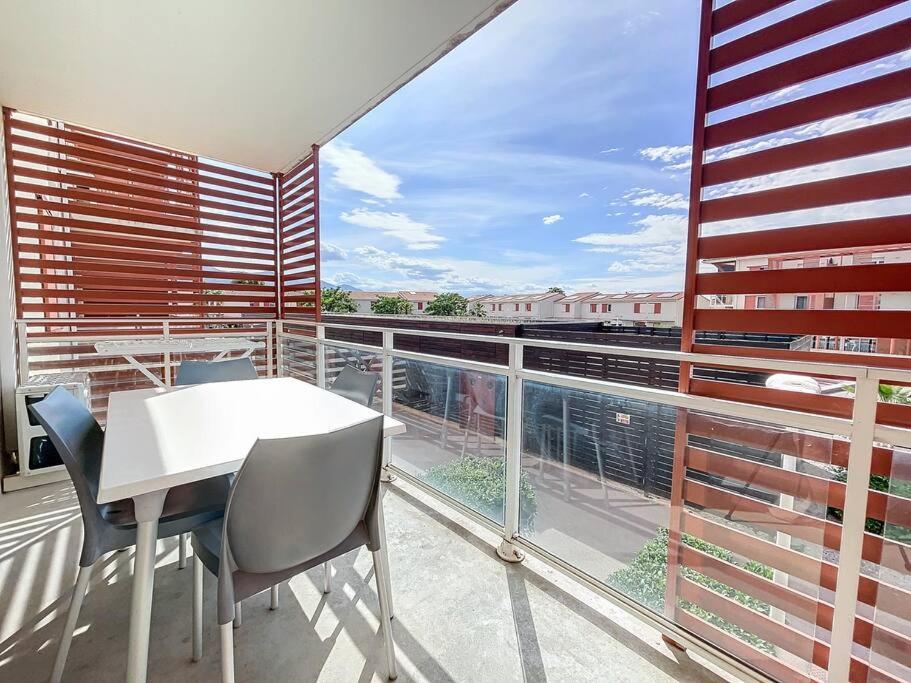 d'un balcon avec une table et des chaises blanches ainsi qu'une grande fenêtre. dans l'établissement 3472-Appartement 6 couchages avec piscine, à Argelès-sur-Mer