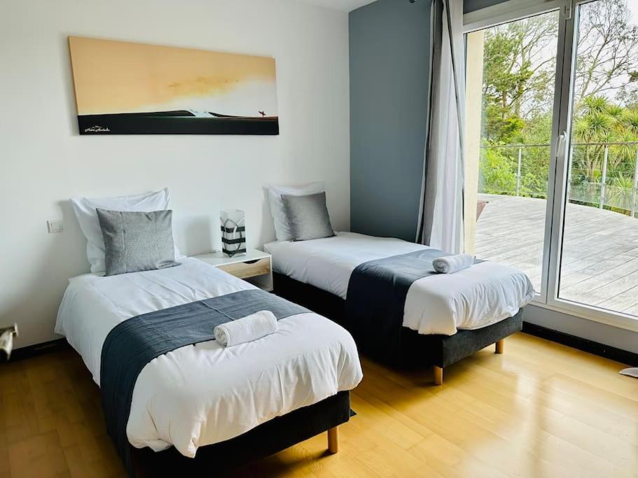 a bedroom with two beds and a window with a balcony at Villa rospico, 200m de la plage avec piscine in Névez