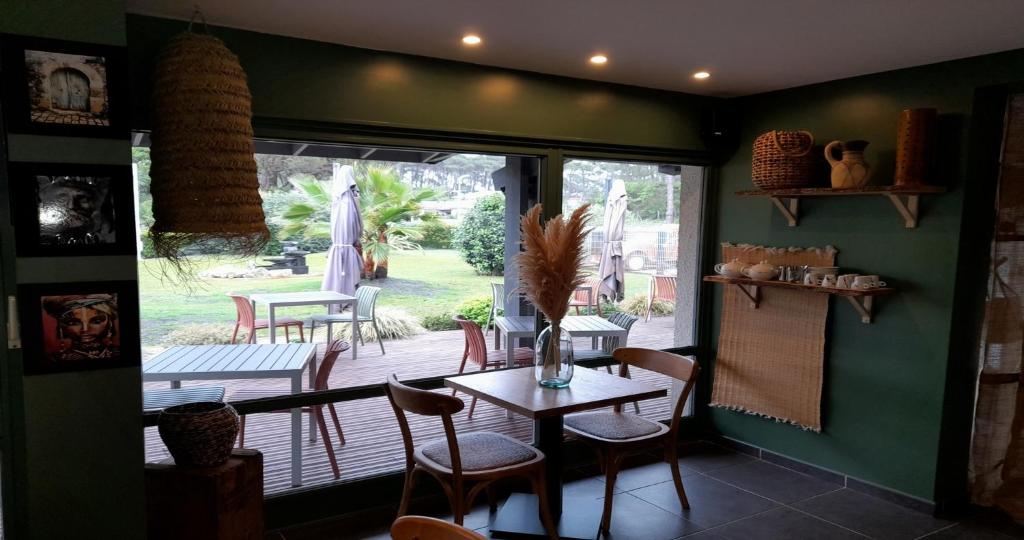 a dining room with a table and chairs and a patio at Les Jardins de L'Ocean - Climatisé in Biscarrosse-Plage