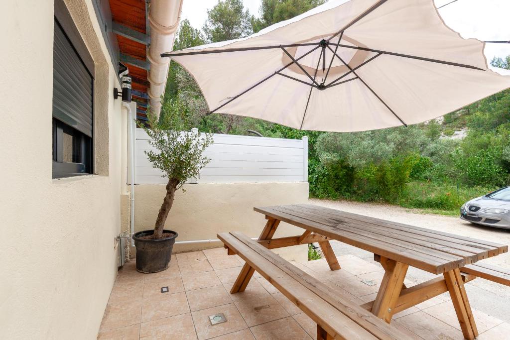 - une table de pique-nique en bois avec un parasol sur la terrasse dans l'établissement Gîte rénové Calanque La Vesse, à Le Rove