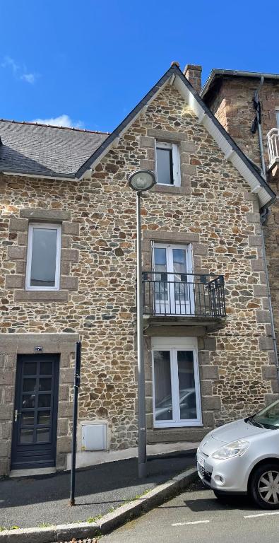 une maison en briques avec une voiture garée devant elle dans l'établissement Ker Levenez - Maison en Pierre Perros-Guirec, à Perros-Guirec