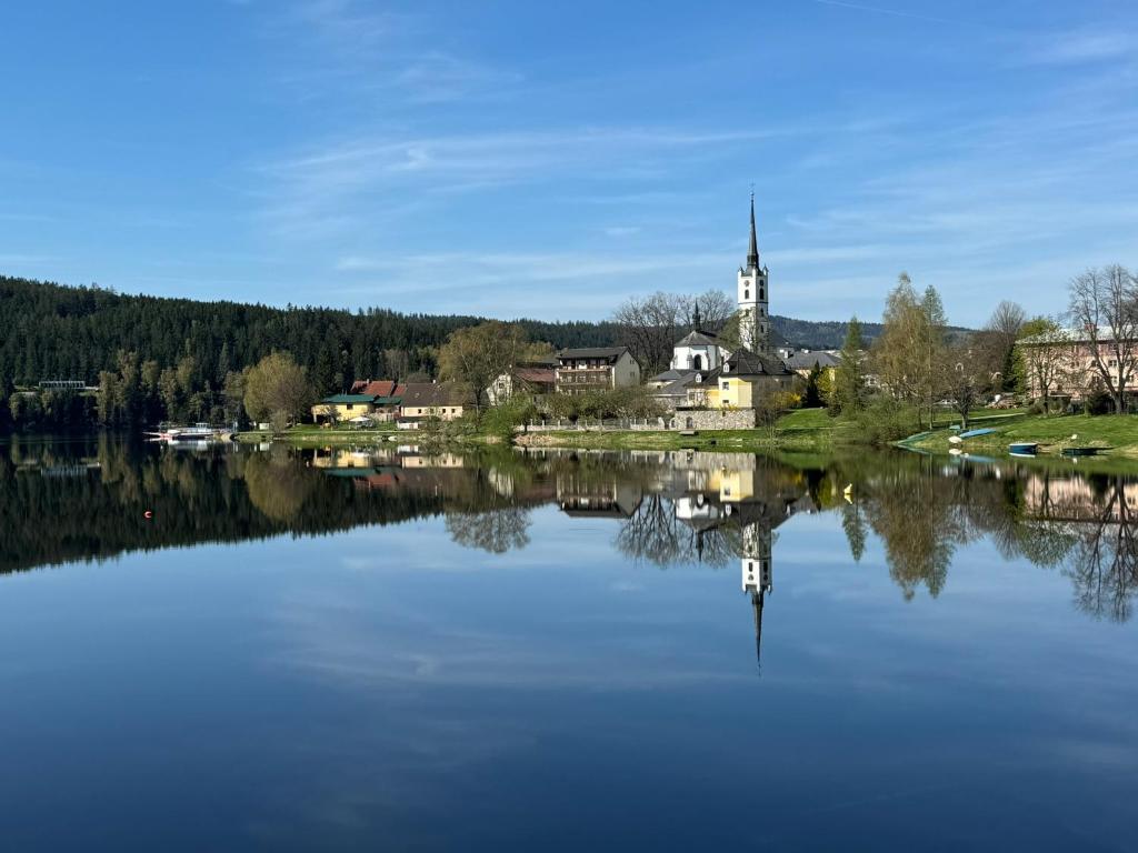 un reflejo de una iglesia en un lago en Wellness & Spa Apartments Lipno - Frymburk en Frymburk