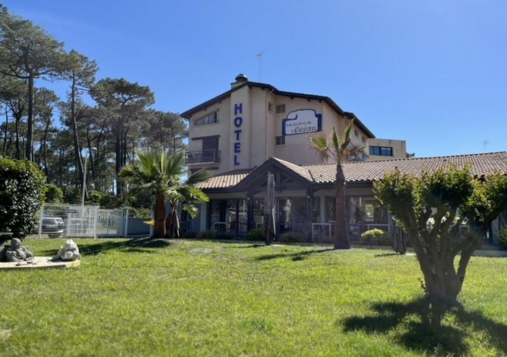 a building with a tree in front of a yard at Les Jardins de L'Ocean - Climatisé in Biscarrosse-Plage