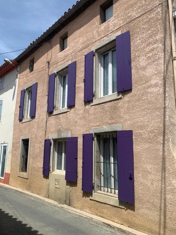 un bâtiment avec des volets violets sur le côté dans l'établissement Maison Ventenac village house, à Ventenac en Minervois