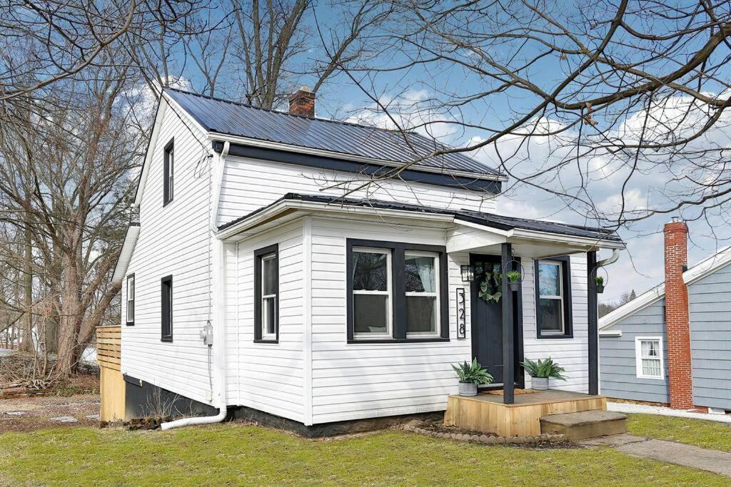 a small white house with a black door at The Towpath Retreat-A Cozy Farmhouse Stay in Canal Fulton