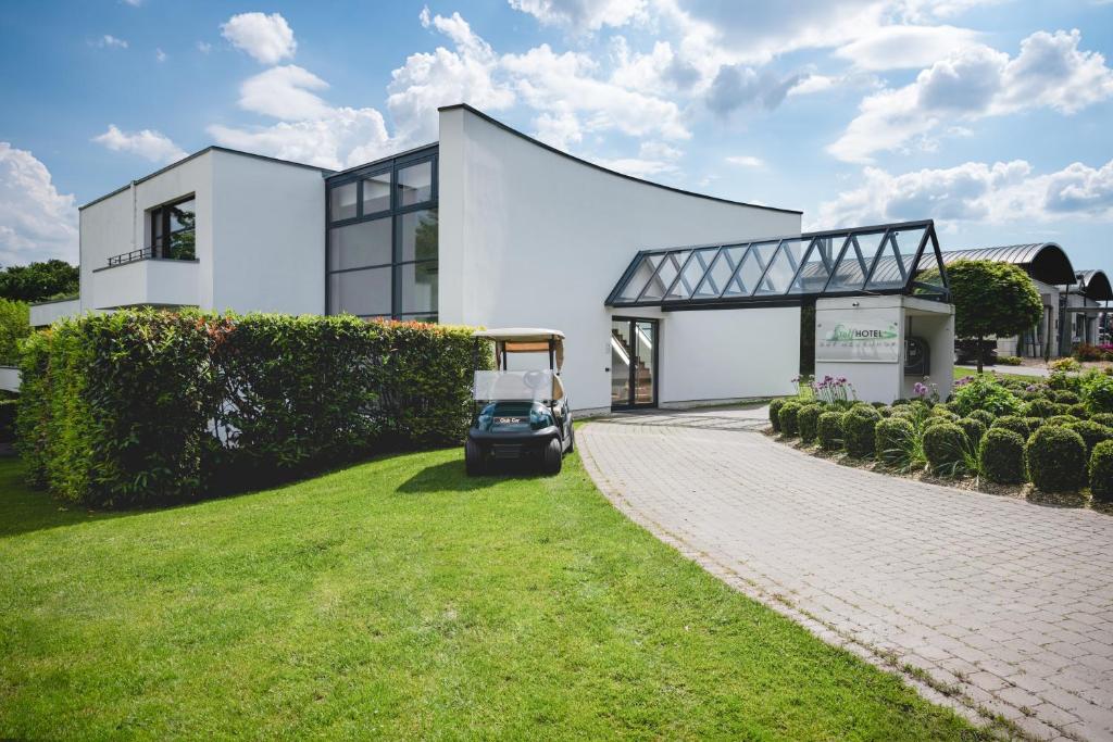 une maison avec une voiturette de golf garée devant elle dans l'établissement Golfhotel Gut Neuenhof, à Fröndenberg/Ruhr