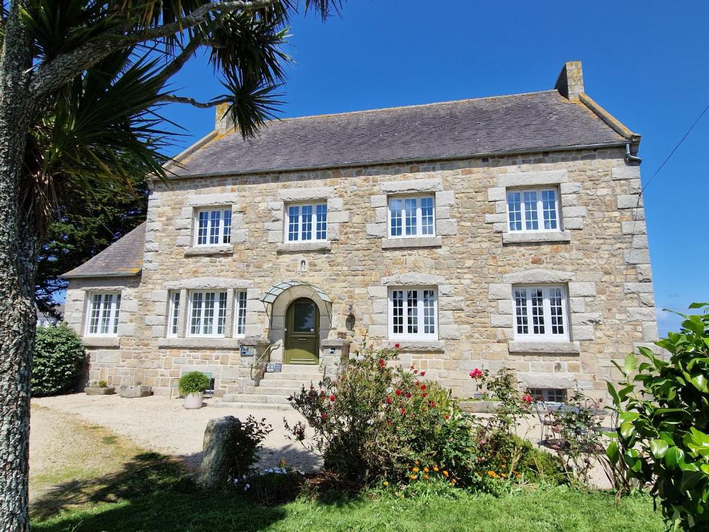 an old stone house with a palm tree at Entre Terre et Mer in Plougoulm