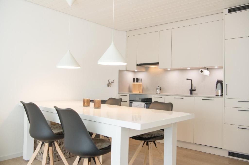 a white kitchen with a white table and chairs at Stylish apartment with mountain view in Lenzerheide