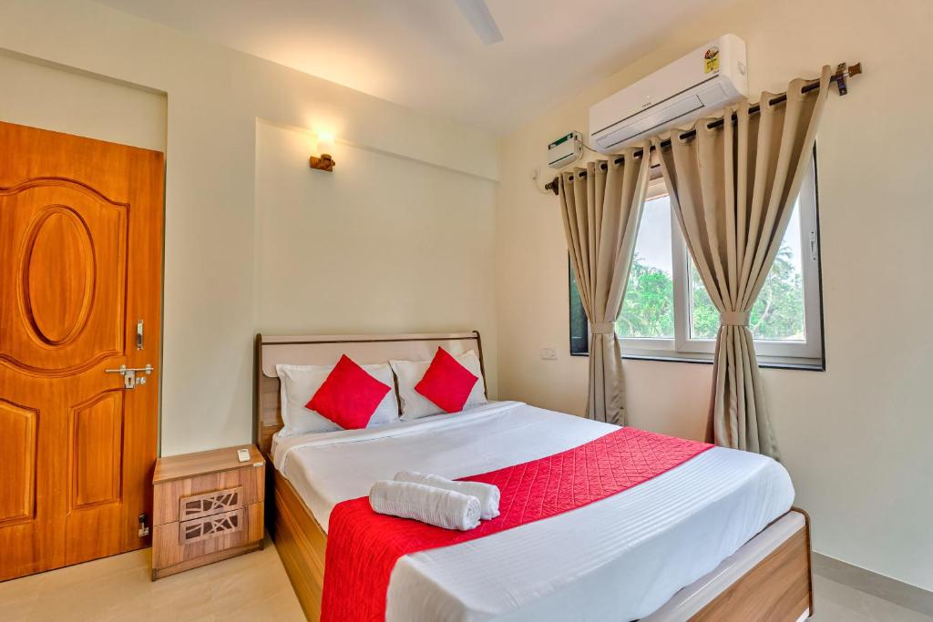 - une chambre avec un lit doté d'oreillers rouges et une fenêtre dans l'établissement Golden Sun Ray's Villas, à Baga