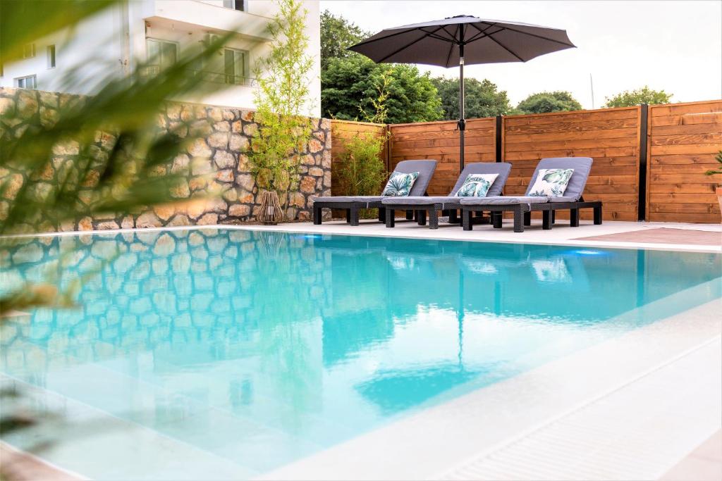 a swimming pool with two chairs and an umbrella at Kiteriders Garden Villas in Ulcinj