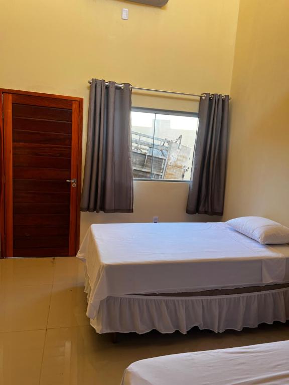 Un dormitorio con dos camas y una ventana. en Pousada do Andrade, en Ponta Porã
