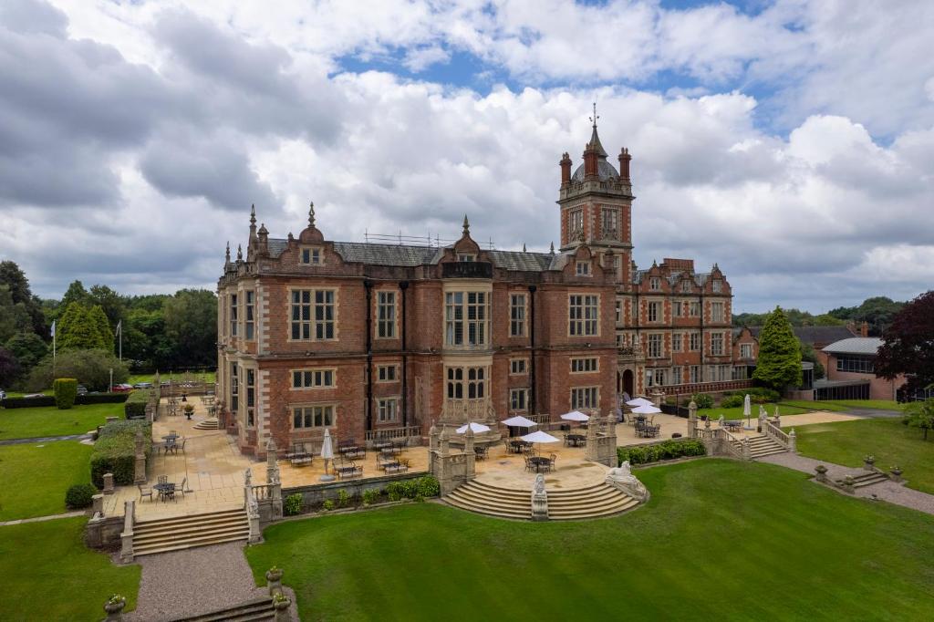 a large brick building with a clock tower on top at Crewe Hall Hotel & Spa - Cheshire in Crewe