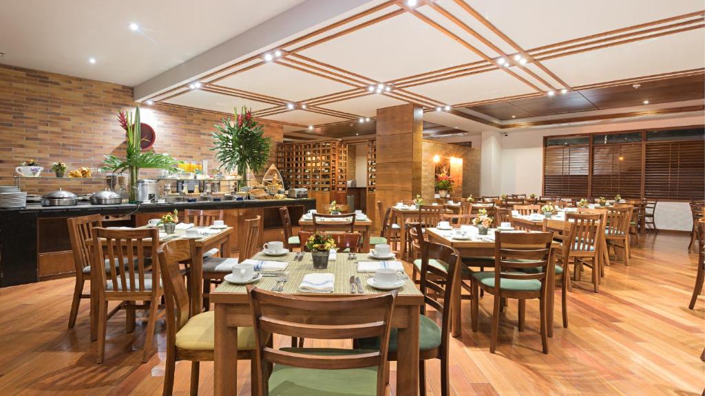 a restaurant with wooden tables and chairs and a bar at Hotel Habitel Select in Bogotá