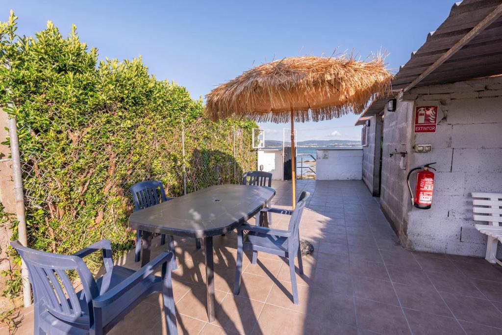 a patio with a table and chairs and an umbrella at Vivienda con jardin y acceso a pequeña playa in O Grove