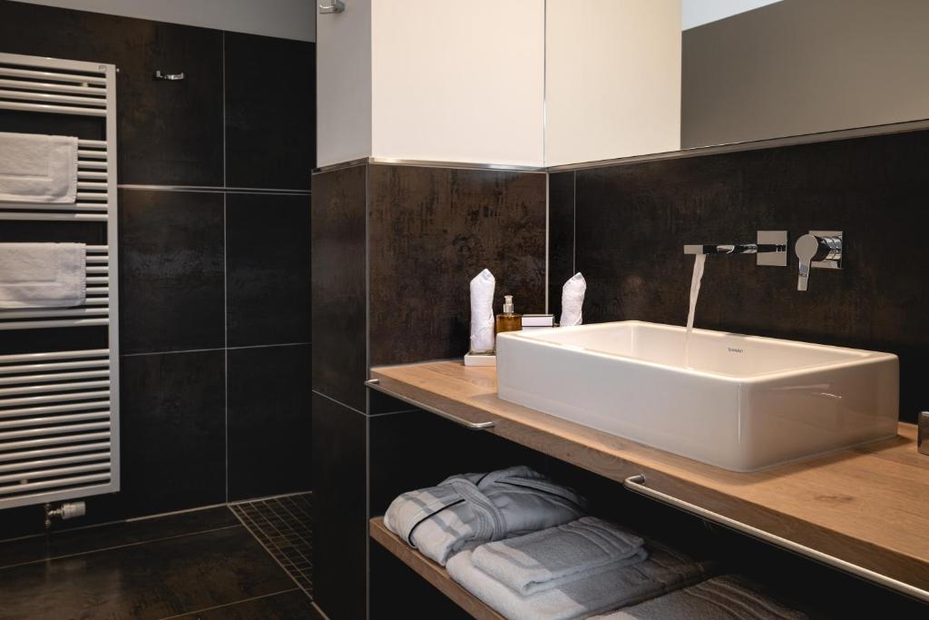 a bathroom with a white sink and black tiles at Golfhotel Gut Neuenhof in Fröndenberg